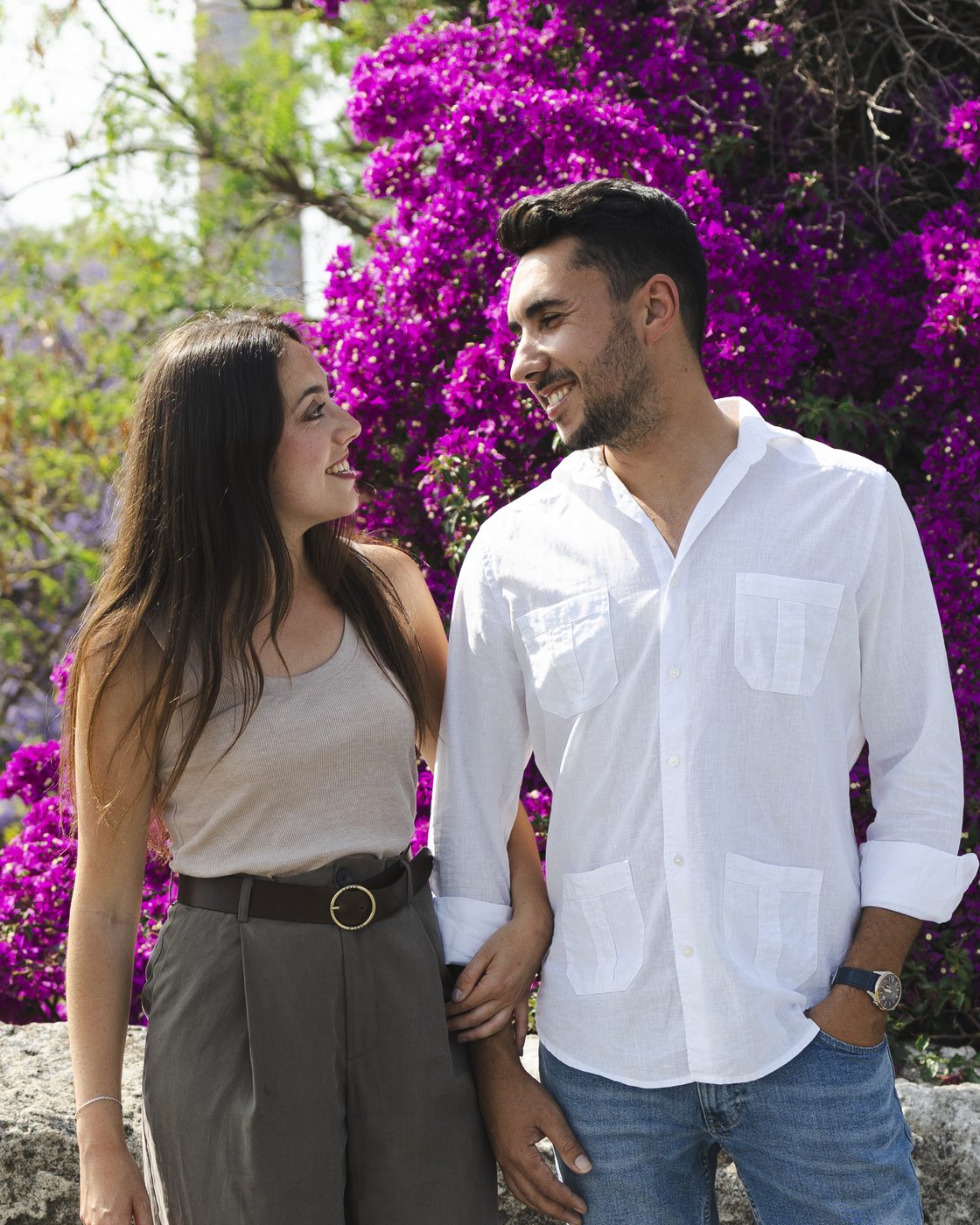 Florine et Cristhian, fondateurs d'IZI Málaga, souriants devant un bougainvillier en fleurs à Málaga